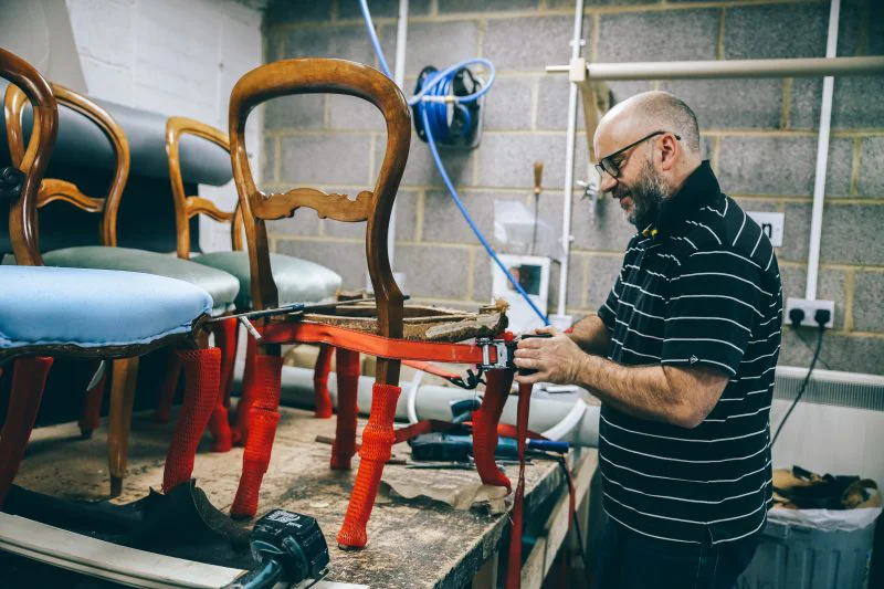 Craftsman working on banquette seating upholstery in a Covent Garden workshop